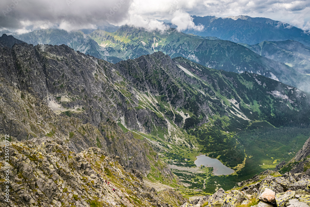 Aerial view from the peak of Jahňací štít down the green valley on a cloudy summer day. Scenic Slovakian Tatra landscape.
