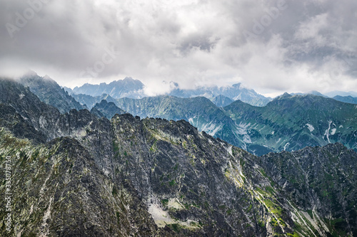 View onto the rugged mountain range of High Tatras seen from the peak of Jah  ac     t  t down on an overcast  summer day. Scenic Slovakian Tatra landscape.