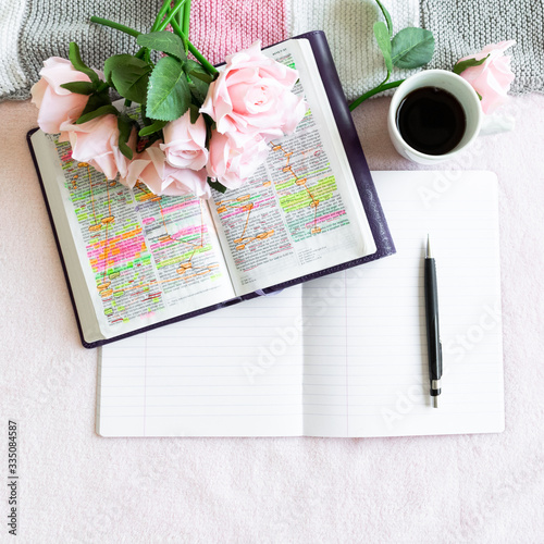 Pink Bible flat lay: Bouquet of pink roses, open Bible, black tea, coffee, journal, notebook, pen and pink blankets. Morning devotional. Rose, white, grey tones. Baselland, Switzerland - 02.04.2020