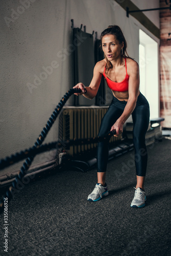 Energetic business woman working out in a gym with ropes - healthy lifestyle successful woman