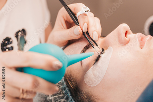 Eyelash extension procedure - the master dries the glue with air from a rubber syringe