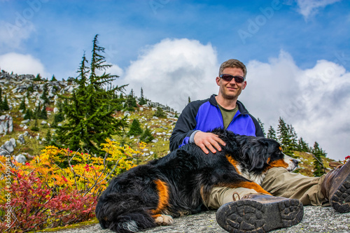 Fotografía Adventurous male hiker sitting with a Bernese Mountain Dog.