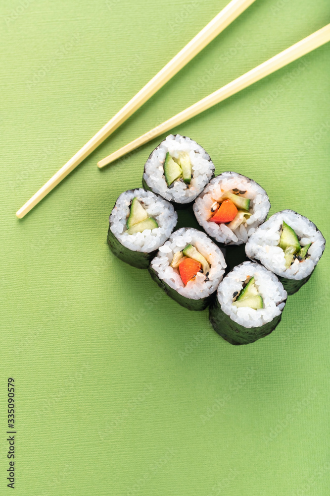 Vegetarian sushi roll set with vegetable filling and chopsticks on a green background Vegetarian sushi roll set with vegetable filling and chopsticks on a green background
