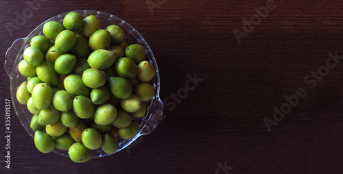 
glass bowl filled with umbu fruit on a dark wooden background