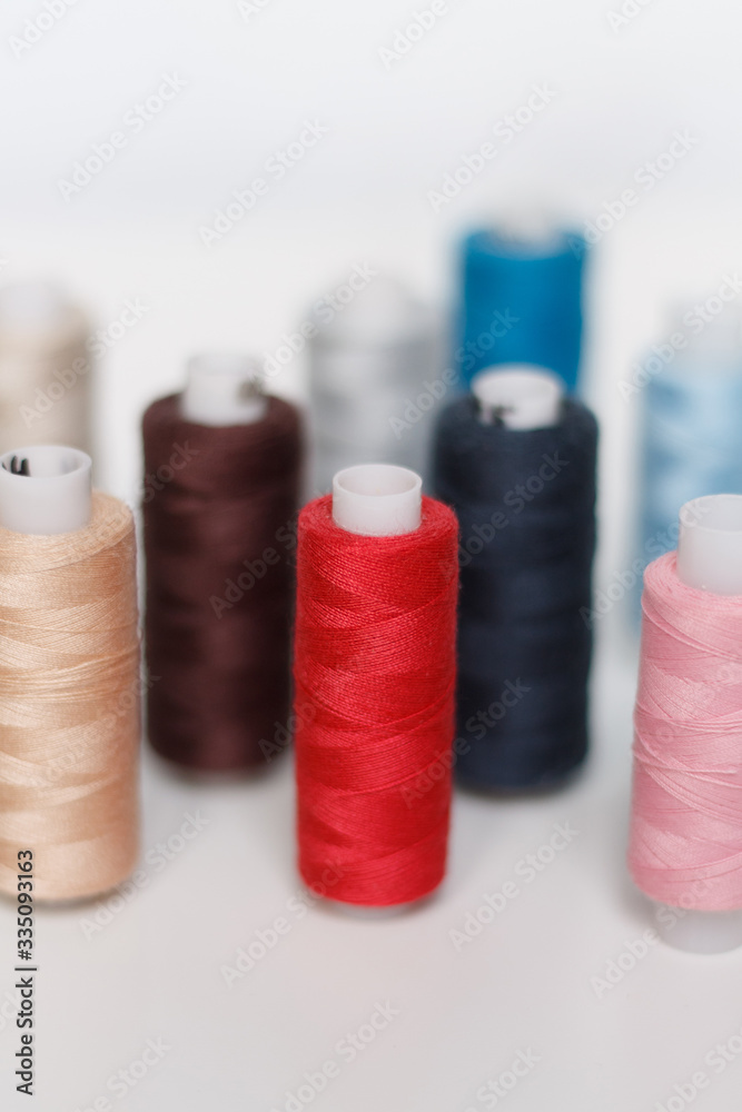 close-up of colored sewing threads on a light background with a place for the inscription. close-up of colored sewing threads on a light background with a place for the inscription.