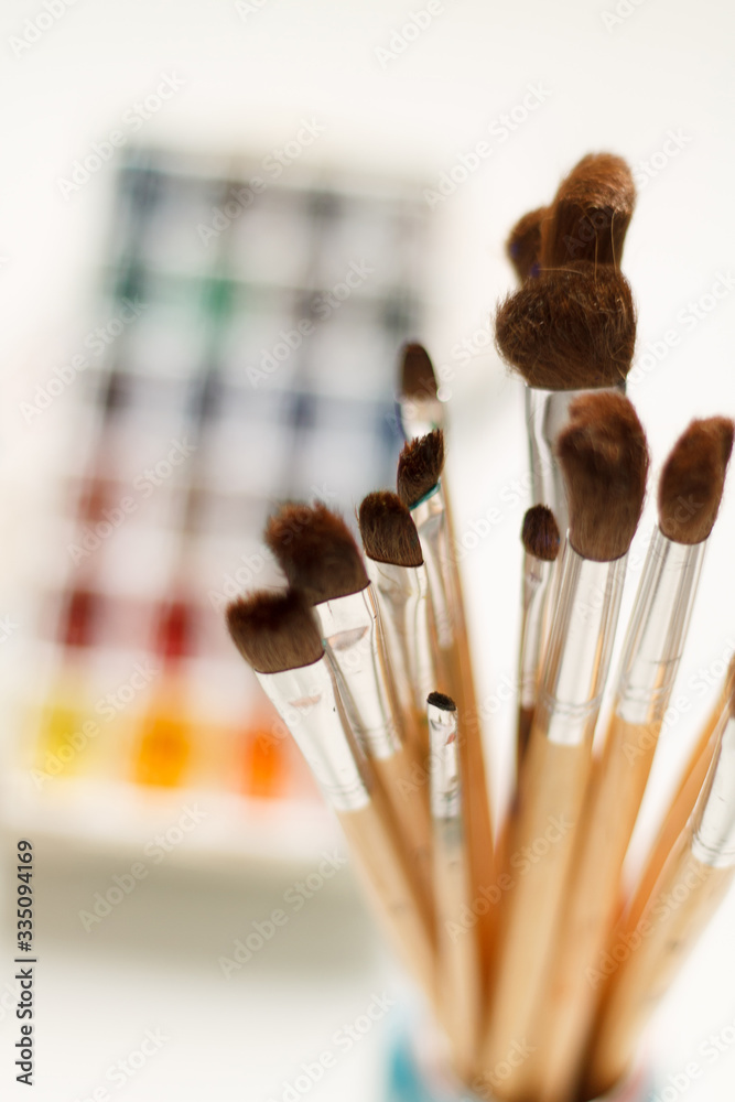 close-up of a paintbrush against a background of watercolor paints with a blurred background. artist's composition - obrazy, fototapety, plakaty 