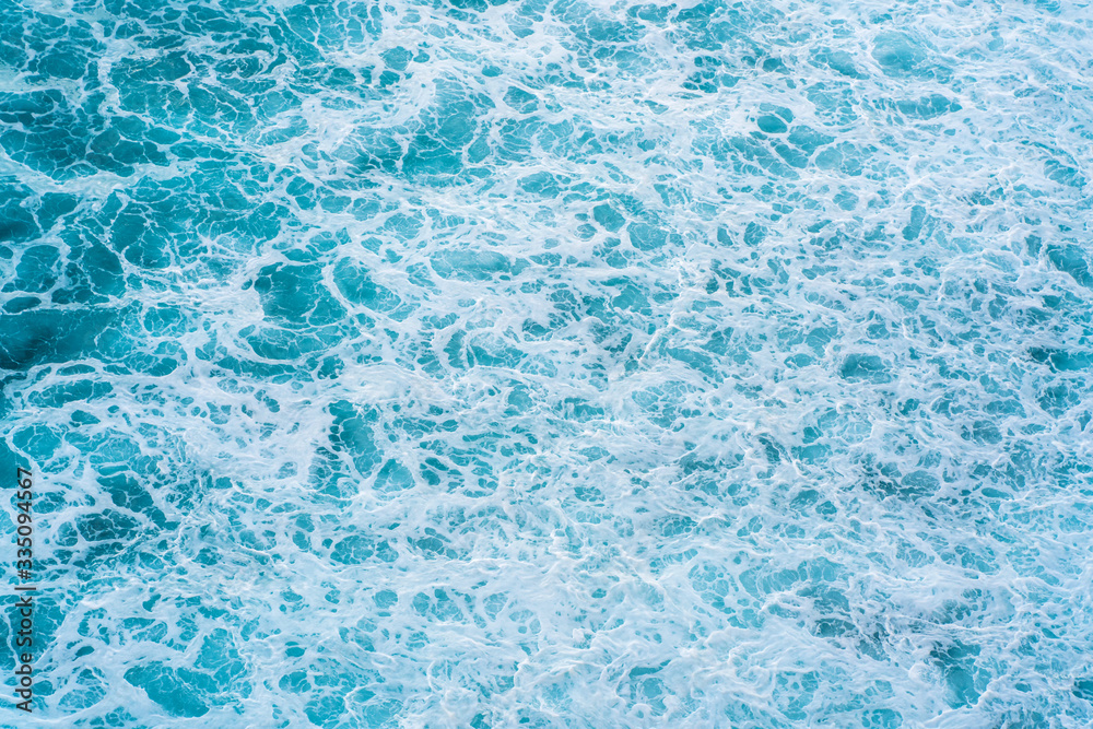 Texture Light blue surface of raging sea water with white foam and wave pattern.The azure surface of the ocean. Aerial photography of water. Azure sea natural background.