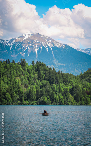 Tourists enjoying beautiful views from the Bled lake while sitting in their canoe