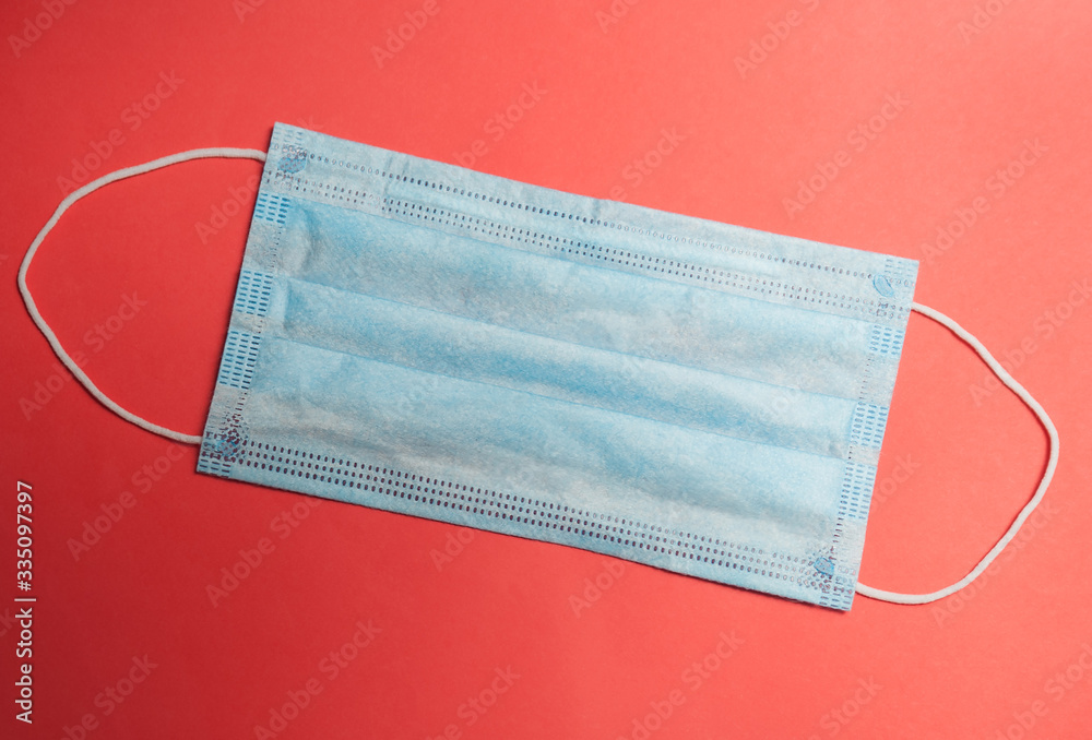 blue medical mask from the virus on a red background lies