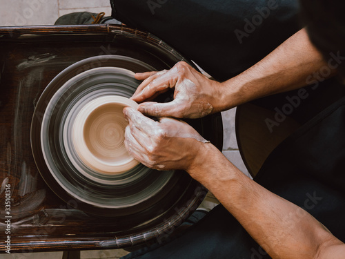 Pottery workshop Top view photo Ceramist is sculpting a bowl behind a rotating potter's wheel