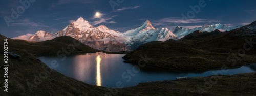 Bachalpsee lake with moon over mountains, scenic night landscape, Swiss Alps, Switzerland.