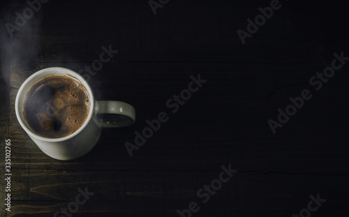 White mug full of hot beverage. Cup of steaming coffee on dark wooden table. Top view, copy space for text.