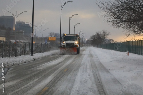 Salt truck plowing the road on a snow covered scene