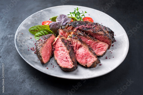 Barbecue dry aged wagyu entrecote beef steak with lettuce and tomatoes as closeup on a modern design plate