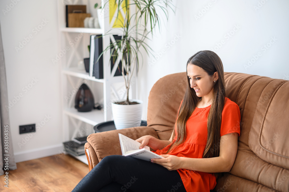Woman sits on the sofa and reads a book Woman sits on the sofa and reads a book