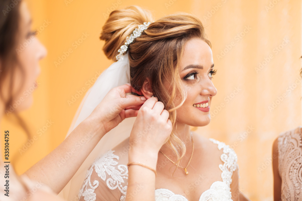 Fototapeta premium bride's girlfriend prepares the bride for her wedding day. The bride's girlfriend helps secure the bride's wedding dress before the ceremony