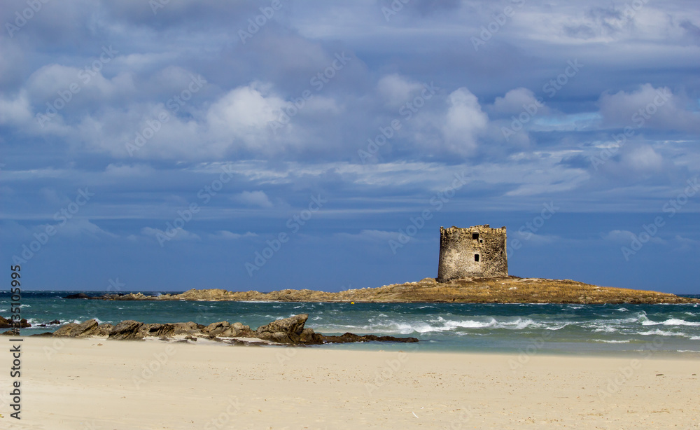 Stunning  view on the old aragonese tower in La Pelosa Beach. beautifull beach with white sands, waves with foam and cloudly sky in Stintino, Sardinia, Italy