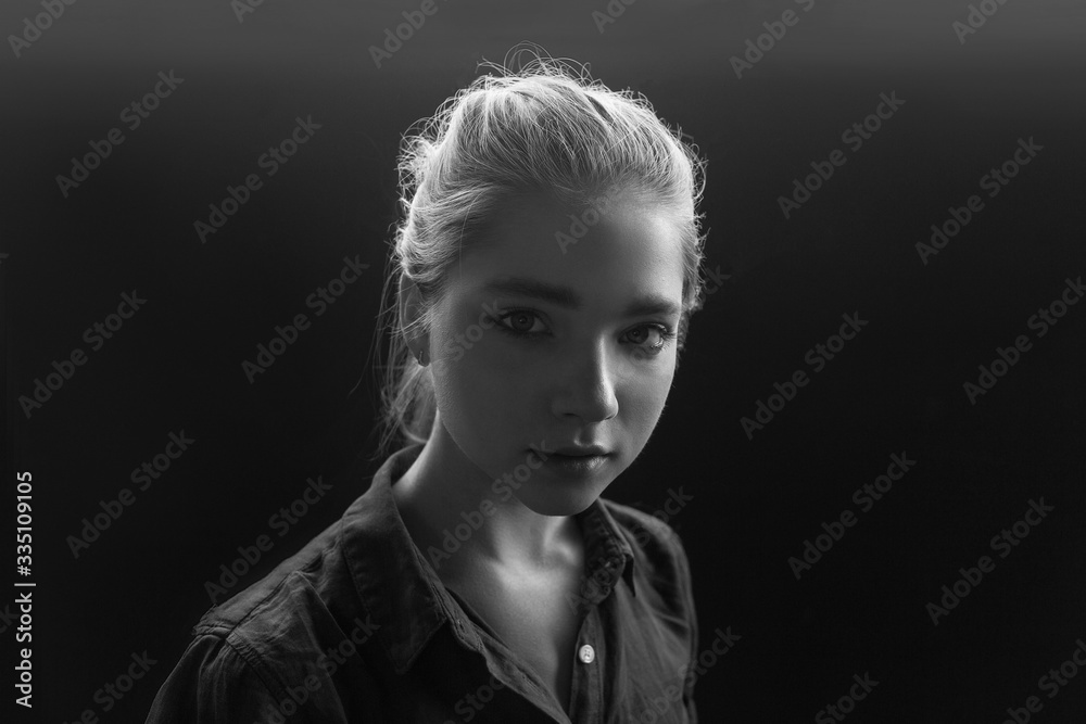 Black and white closeup portrait of young pretty sensual girl in checkered shirt posing tilting her head. her hair is gathered behind and backlit, her eyes are summed up with mascara. model tests
