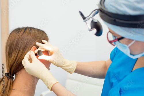 ENT doctor with tools  a mask and gloves examines the patient s ears. Otolaryngologist with her.tool