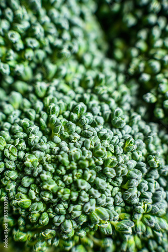 Fresh broccoli in a wooden bowl. Close-up shot. Black background. Top view. Space for text.