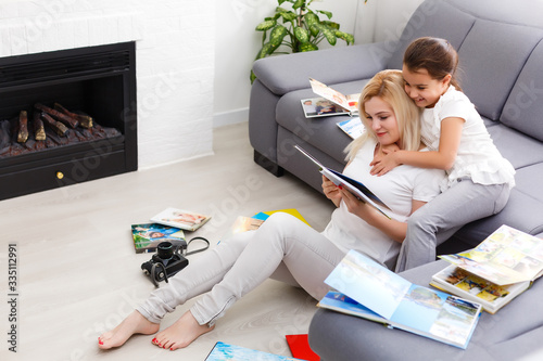 mother and daughter enjoying photo album in livingroom photo