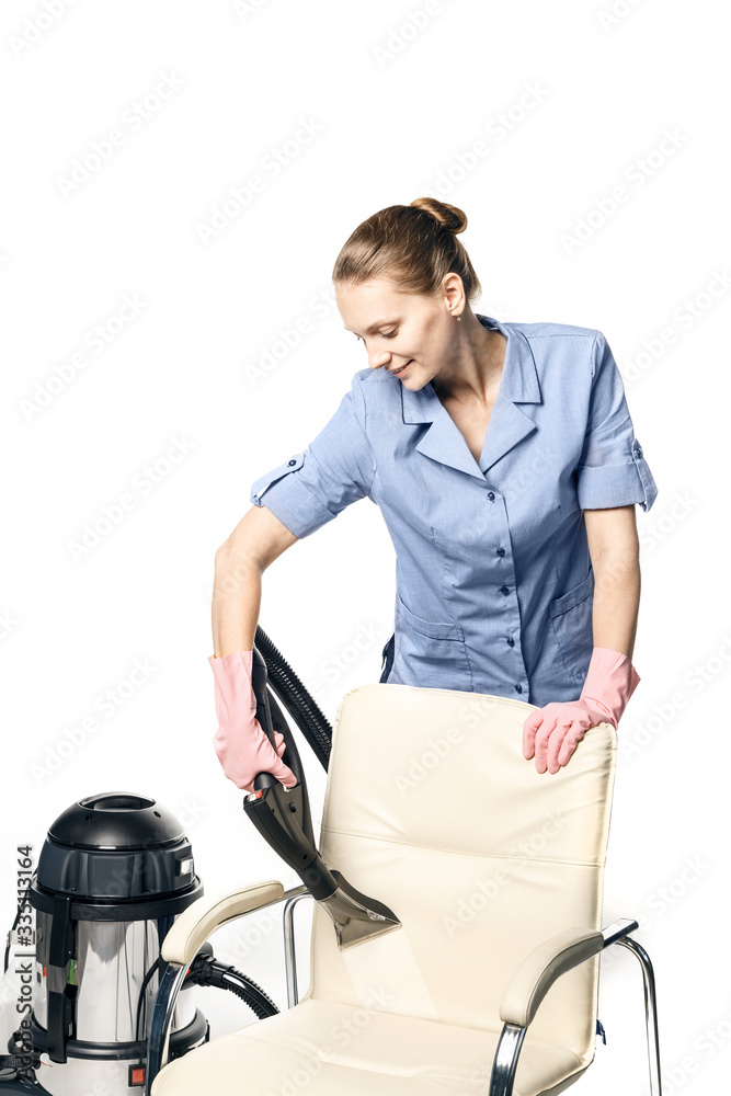 Young white woman in maid uniform is steam-cleaning an armchair isolated on a white background. Young white woman in maid uniform is steam-cleaning an armchair isolated on a white background.
