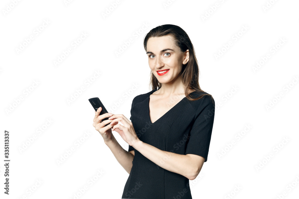 Business woman (fatal woman) in a black dress with red lipstick looks at her phone, isolated on a white background. Business woman (fatal woman) in a black dress with red lipstick looks at her phone, isolated on a white background.