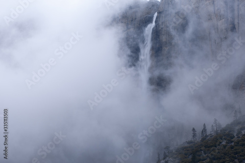 Winter landscape of Upper Yosemite Falls in fog captured with motion blur, Yosemite National Park, California, USA