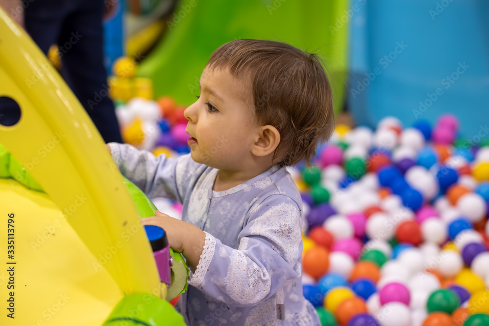 ittle cute toddler girl in a dress peeks over a side with interest on the background of a pool with balls ittle cute toddler girl in a dress peeks over a side with interest on the background of a pool with balls