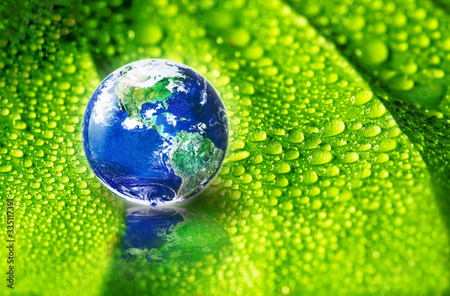 Fototapeta Naklejka Na Ścianę i Meble -  Earth on green leaf with drops of water in soft sunlight, The world need refreshment concept and Environmental concept, Elements of this image furnished by NASA