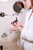 A young girl in the bathroom applies hand cream. The face is out of focus. Copy of the space.
