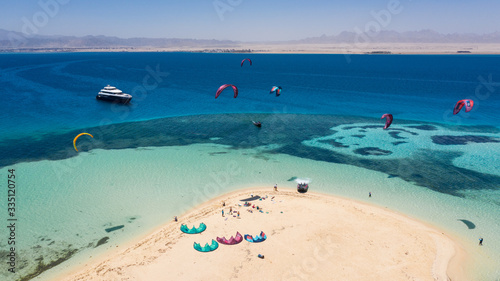 Aerial view of a yacht and a beautiful island and many kitesurfers on the Red Sea in Egypt © Антон Яковлев