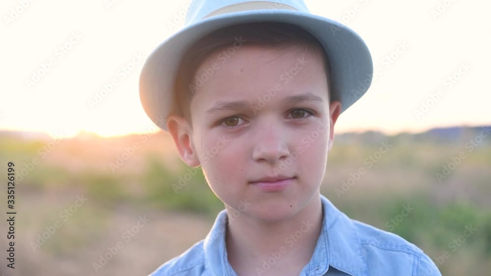 Boy in hat is dancing on the field at the sunset Boy in hat is dancing on the field at the sunset