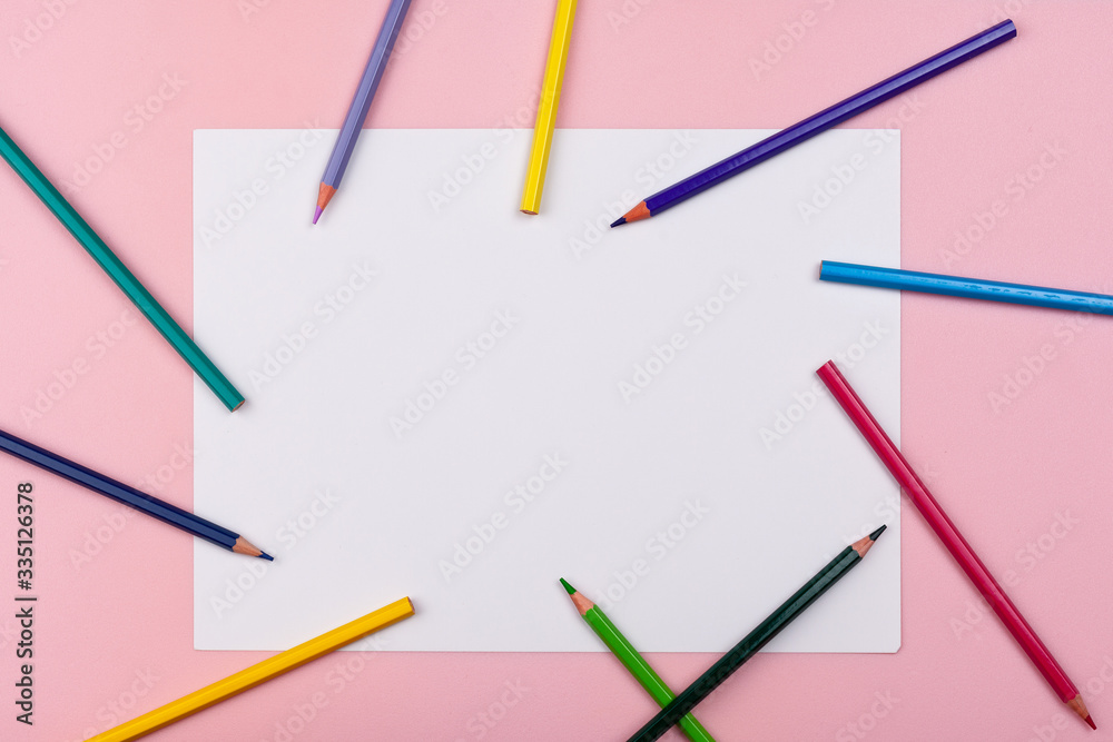 white sheet on a pink background. colored pencils are scattered around the perimeter white sheet on a pink background. colored pencils are scattered around the perimeter