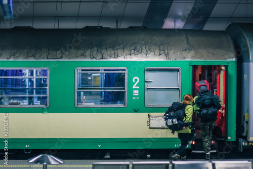 Fototapeta Naklejka Na Ścianę i Meble -  Exterior of Polish green sleeping train wagon, standing on a platform on a train station in Krakow with backpackers going aboard. Backpack traveling with a train.