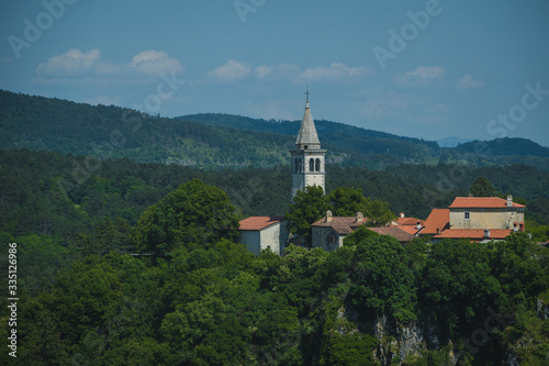 Village of Skocjan  with a visible bell tower of St. Kancijan church  rising way above the Skocjan Caves gorge on a summer day.