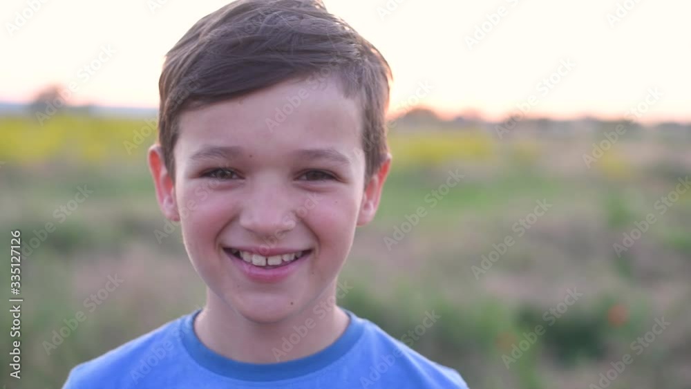 Handsom brunette boy stays and smiling in field Handsom brunette boy stays and smiling in field