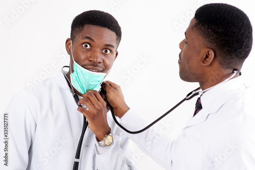 Two young african doctors on an isolated white background with a phonendoscope. One of them with mask.