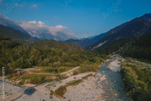 Wild camping in italian Julian alps in the valley of Resia. Evening view of Resia river with campervan seen on the edge of water basin