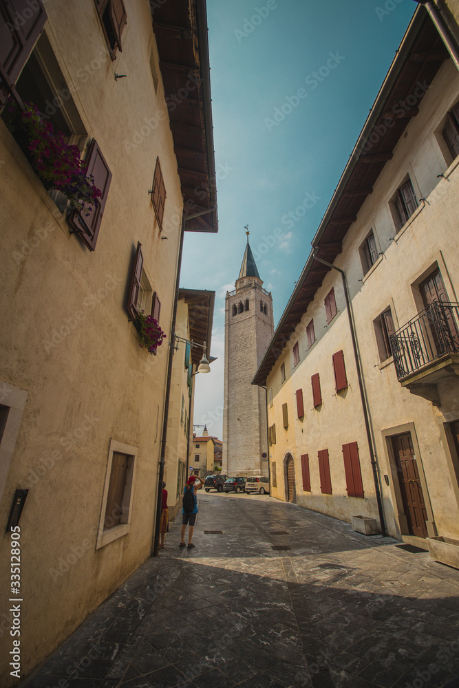 The streets of old town in venzone, italy, looking towards beautiful belltower rising high up.