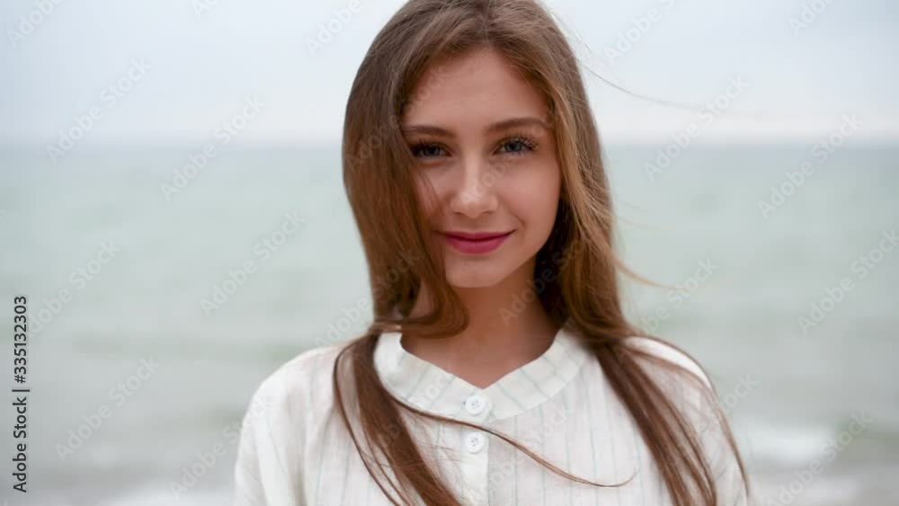 Beautiful girl with long brunette hair in a white linen dress at a seaside closeup Beautiful girl with long brunette hair in a white linen dress at a seaside closeup