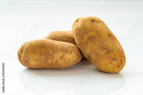 Close up of three russet potatoes on white background