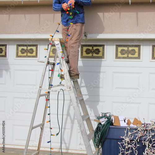 Man stringing Christmas lights on his house. photo