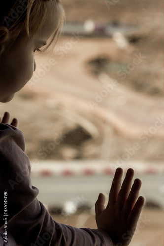 Lonely child looks out the window in quarantine conditions