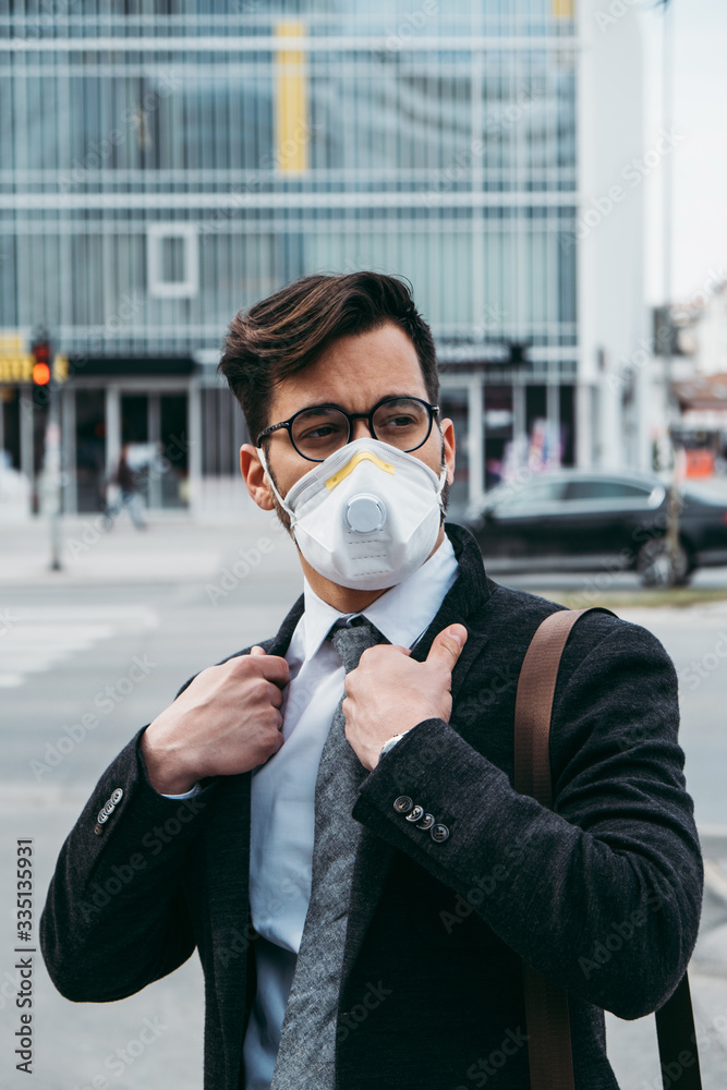 Business man standing or walking on city street with protective face mask. Virus epidemic concept.