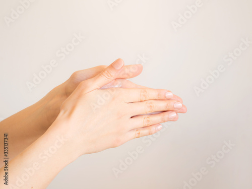 Female hands cleaning washing with sanitizer gel over bright gray background
