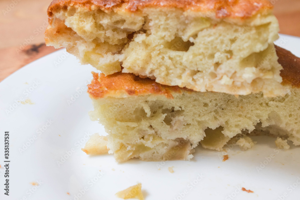 Sweet homemade cakes with apples. Two slices of sponge Apple pie with a brown crust on a white plate close up Sweet homemade cakes with apples. Two slices of sponge Apple pie with a brown crust on a white plate close up