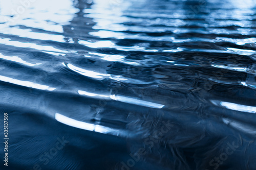 Closeup of calm water surface texture with waves in dark blue color. Trendy fresh abstract nature background. 2020 color concept photo