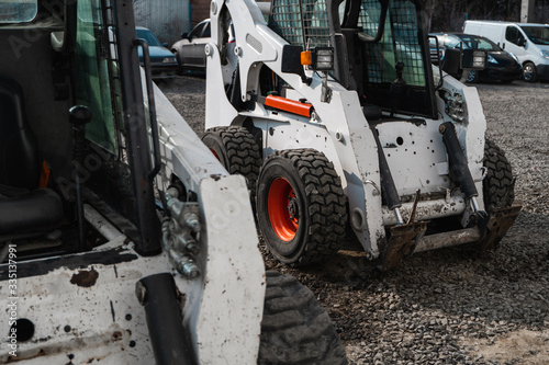 Two white skid steer loader at a construction site waiting of work. Industrial machinery. Industry. photo