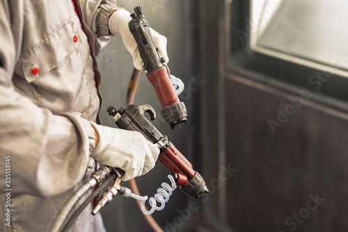Paint shop worker with industrial sprayers in his hands